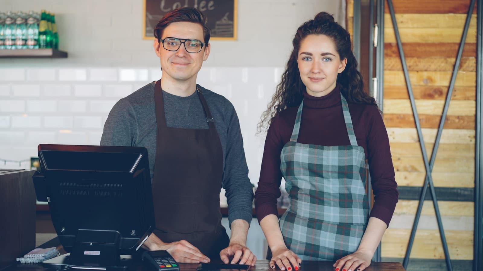 Two people behind the counter of a small coffee shop