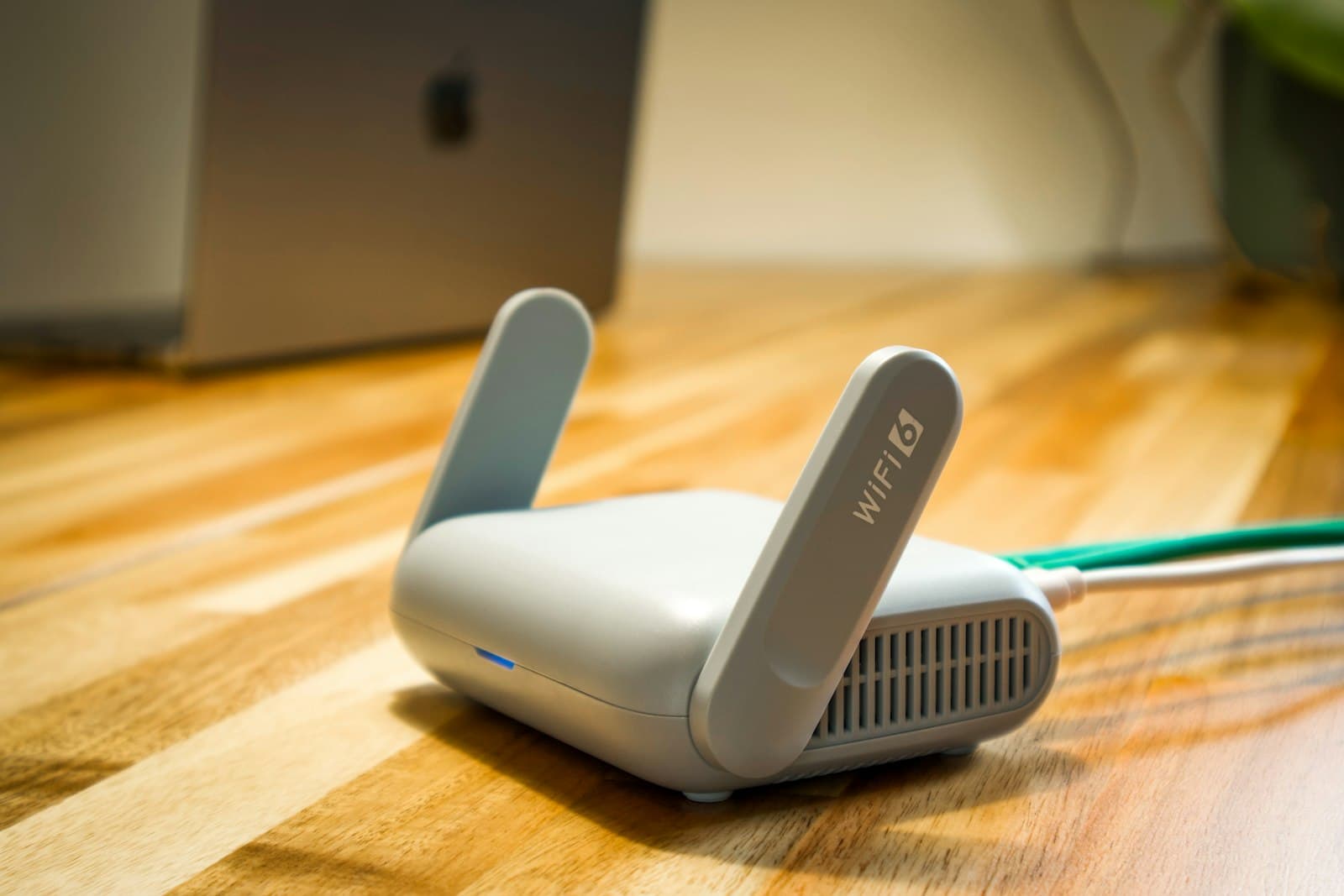 Wi-Fi 6 router on a wooden table next to a laptop