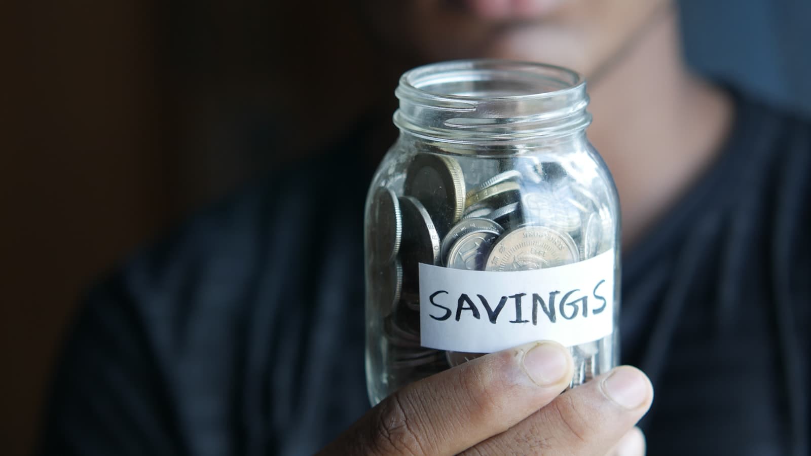 Hands holding a glass jar labelled savings