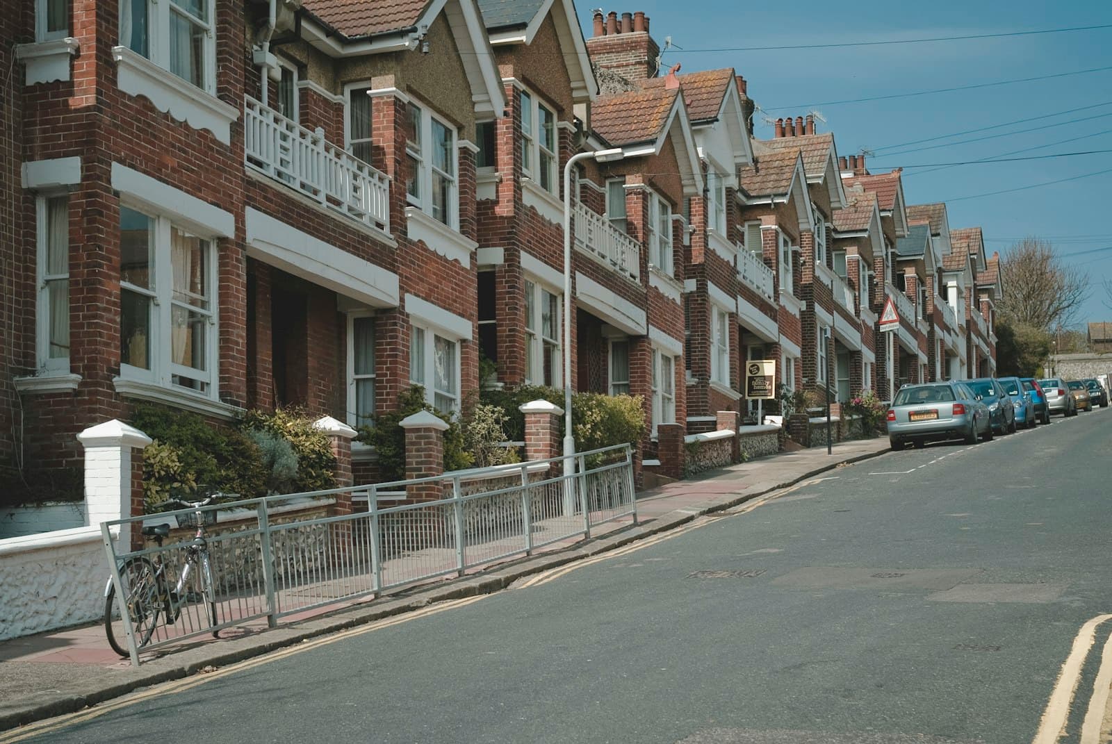 Red-brick terraced houses on a British street with parked cars